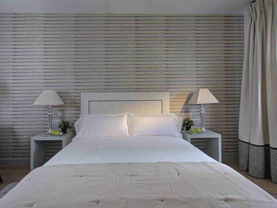 A neatly made bed with white linens, two bedside tables with lamps, and a headboard.