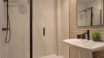 A modern bathroom with a glass shower enclosure, a white sink, and a wooden wall panel.
