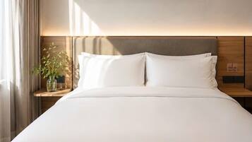 A modern hotel room with a large bed, a nightstand with a lamp, a wall-mounted artwork, and a window with curtains.