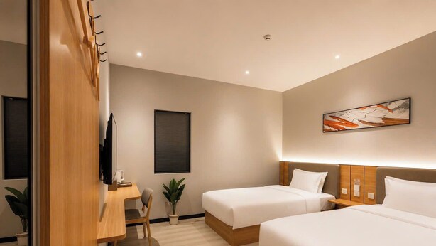 A hotel room with two beds, a desk, a chair, a TV, and a painting on the wall. - Sevendays Hotel (My Hanh)