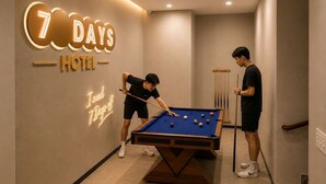 A pool table in a hotel room with a neon sign indicating '7 DAYS HOTEL' and a neon sign saying 'I need your off.' - Sevendays Hotel (My Hanh)