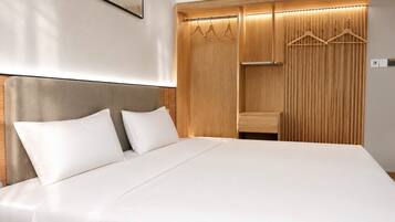 A bed with a headboard, a wooden wardrobe with a mirror, and a hanging light fixture.