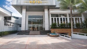 A hotel entrance with a modern design, a sign reading '7 DAYS HOTEL,' and a palm tree in the foreground. - Sevendays Hotel (My Hanh)