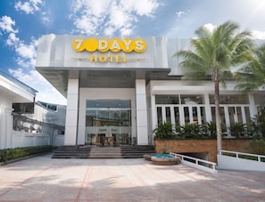 A hotel entrance with a modern design, a sign reading '7 DAYS HOTEL,' and a palm tree in the foreground. - Sevendays Hotel (My Hanh)