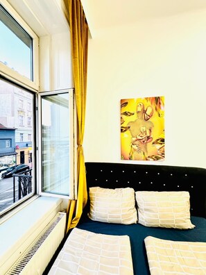 A room with a bed, a window with curtains, and a city view. - Stylish 9BR Apartment for 18 Guests (Vienna)