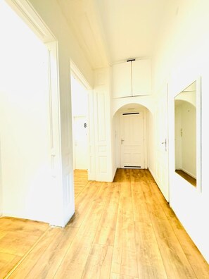 A hallway with wooden flooring, white walls, and doors. - Stylish 9BR Apartment for 18 Guests (Vienna)