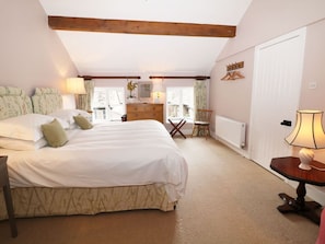 A bedroom with a large bed, a dresser, a chair, and a table with a lamp. - The Bothy, Wildboarclough (Macclesfield)