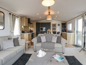 En hyggelig stue med en sofa, sofabord og et køkken i baggrunden.