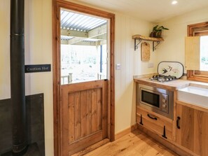 A kitchen with wooden cabinets, a stove, and a caution sign on the door. - Bracken Fern, Eppleby (Richmond)