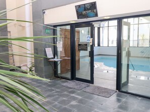 En hotellentrédörr med en glasdörr, en pool som syns genom dörren och en skylt som visar var poolområdet ligger.