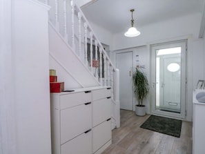 A staircase with white railings, a potted plant, a door with a glass panel, and a light fixture.