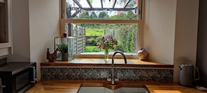 Eine Küche mit Fenster, Spüle, Mikrowelle und einer Blumenvase.