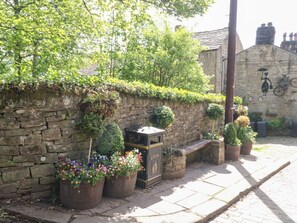 A stone wall with potted plants and a vintage mailbox. - Penny Cottage, West Yorkshire. (Keighley)