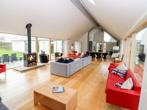 A spacious living room with a fireplace, a red sofa, a grey sofa, and a wooden coffee table. - The Den, Dunecht near Aberdeen (Westhill)