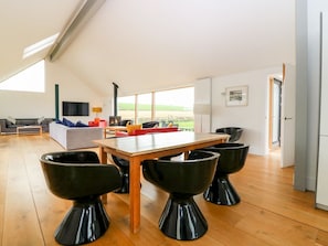 A spacious living area with a high ceiling, a dining table with four black chairs, a sofa, and a TV. - The Den, Dunecht near Aberdeen (Westhill)
