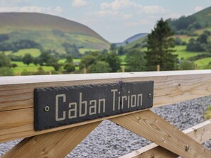 Ein hölzernes Schild mit der Aufschrift 'Caban Tirion' auf einer Metallplatte.