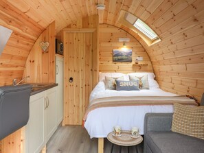Ein gemütliches Holzinterieur mit einem Bett, einer kleinen Küchenzeile und einem runden Tisch mit Tassen.