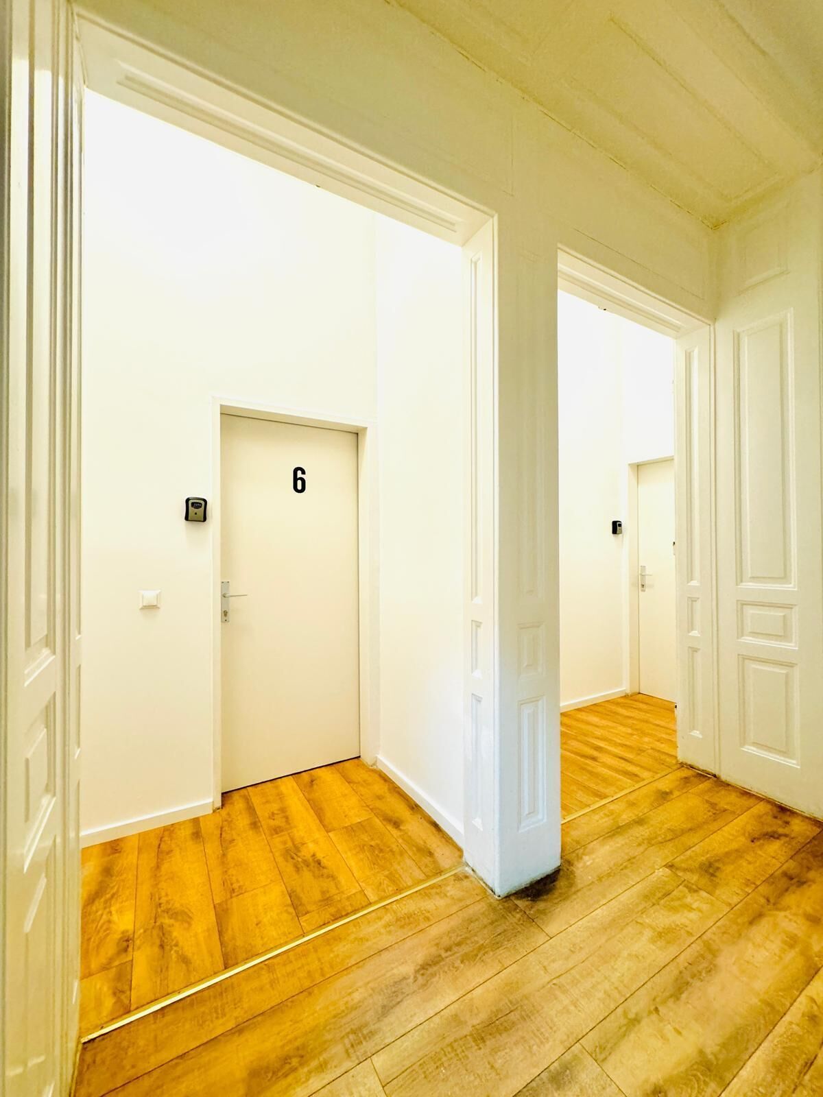 A corridor with wooden flooring and white walls, featuring doors numbered 6 and 7.