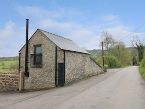 A stone building with a metal roof, a black door, and a window. - The Bottling Shed near Matlock (Matlock)