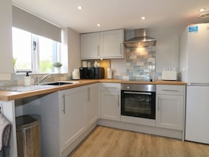 A modern kitchen with white cabinets, a stainless steel range hood, and a built-in oven. - The Bottling Shed near Matlock (Matlock)