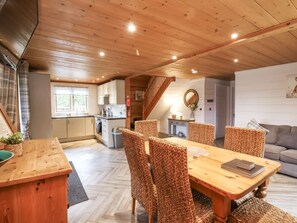 Un'ampia cucina con mobili in legno, una sala da pranzo con sedie in vimini e una scala che conduce a un piano superiore.