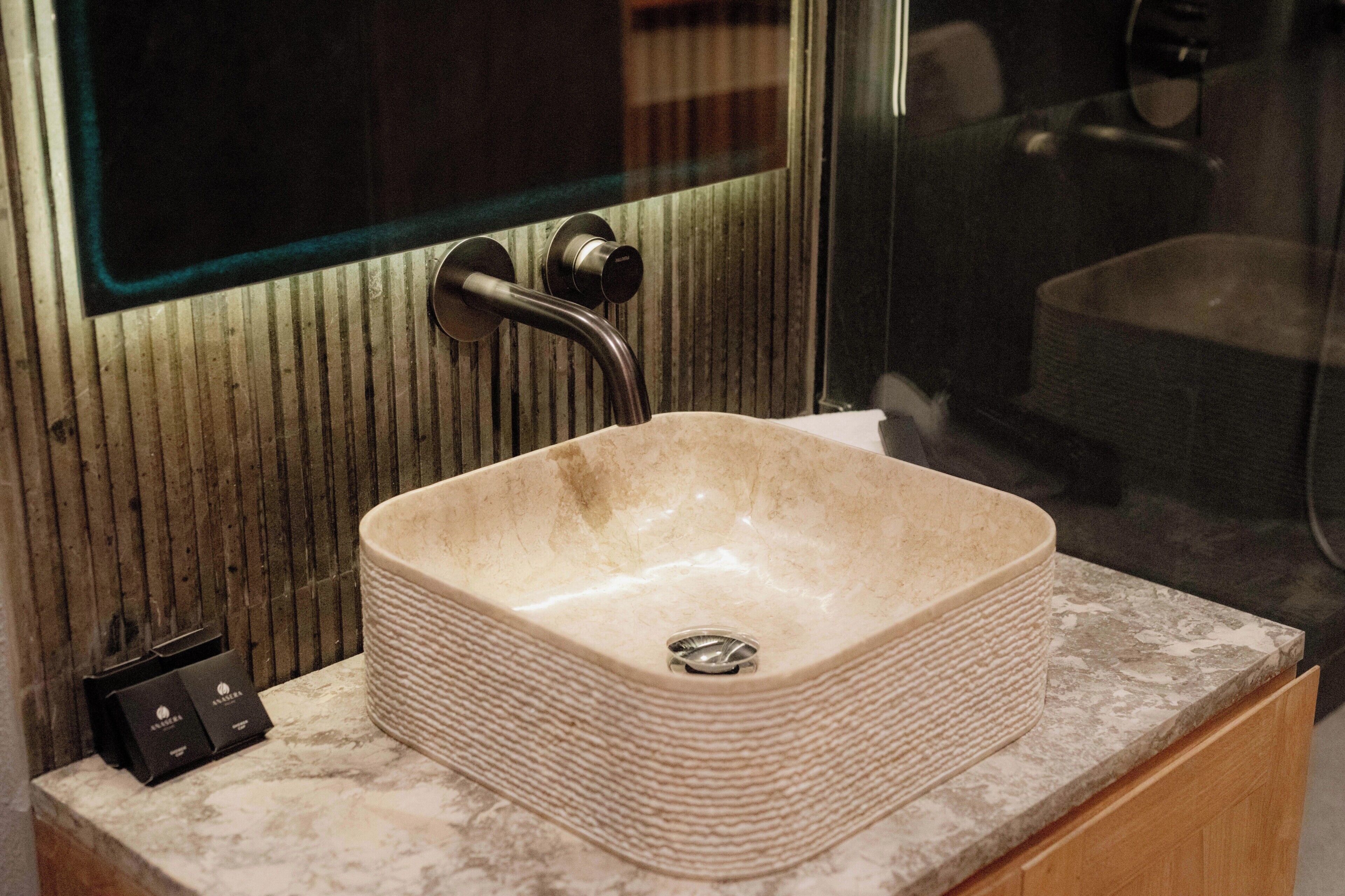 Un baño con un lavamanos rectangular, un espejo y un armario de madera.