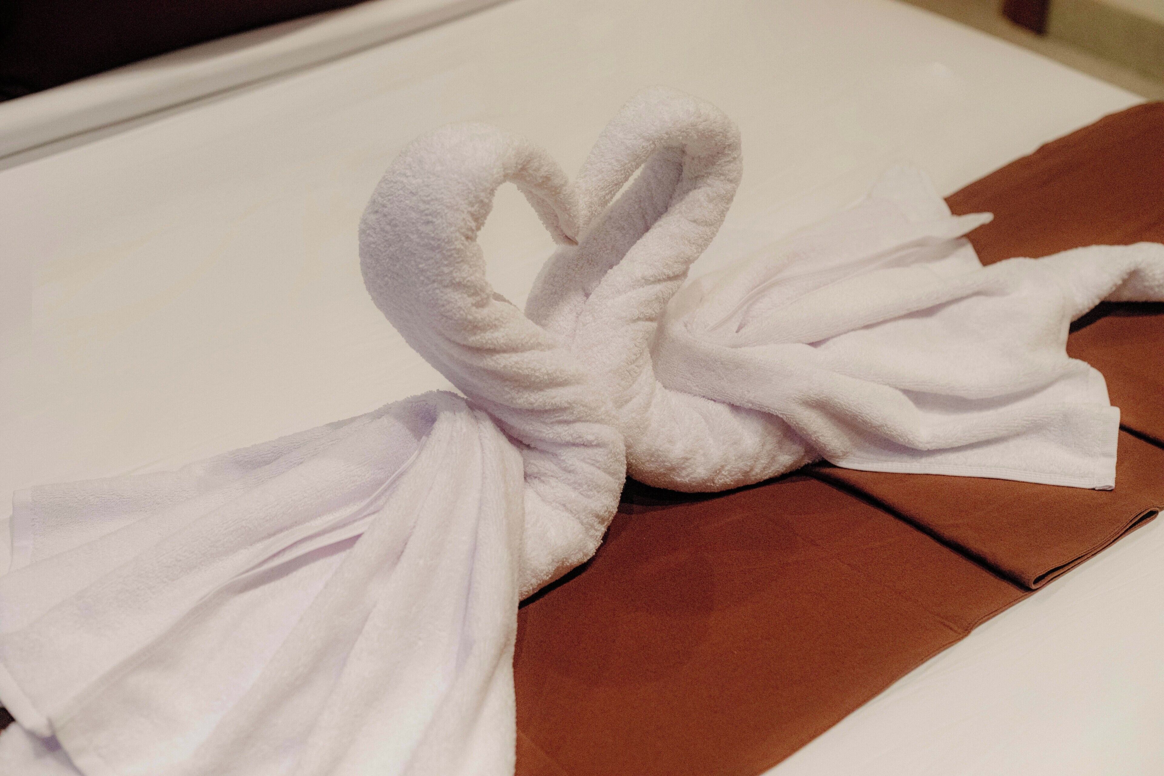 Una toalla blanca doblada en forma de corazón sobre una cama.