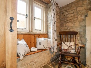 A rustic room with a wooden bench, a wooden rocking chair, and a stone wall. - 33 Main Road Higham Derbyshire (Alfreton)