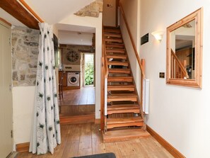 A wooden staircase leading to a laundry area with a stone wall and a mirror on the right. - 33 Main Road Higham Derbyshire (Alfreton)