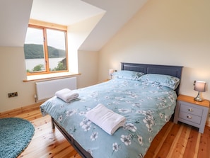 Un dormitorio con cama, mesita de noche, ventana con vistas y tragaluz.