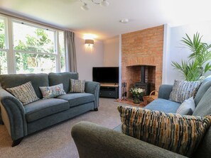A living room with a sofa set, a fireplace, a flat-screen TV, and a large window.