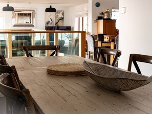 A dining area with a wooden table, chairs, and a large woven bowl. - Swyn Llyr, Rhosneigr, Anglesey (Rhosneigr)