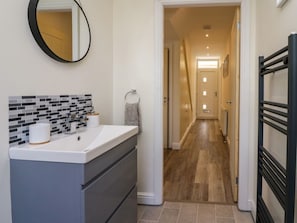Een badkamer met een wit wastafelmeubel, een spiegel en een betegelde spatwand.