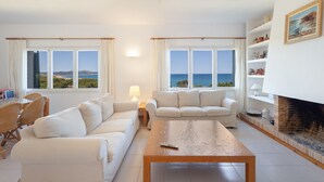 Un salon avec un canapé, une table basse, une cheminée et une vue sur la mer.