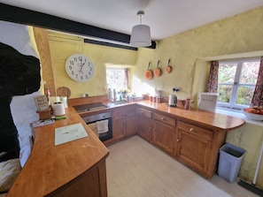 Una cocina con armarios de madera, un reloj y una ventana con cortinas.