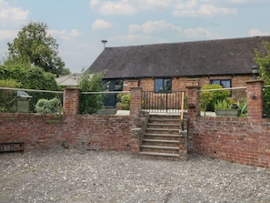 A brick house with a tiled roof, a set of stairs leading to a gated entrance, and a gravel driveway. - Brookley Barn Windley Duffield (Belper)