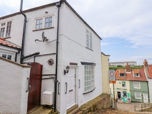 A white building with a red door, a satellite dish, and a pedestrian zone sign. - Steps Cottage, North Yorkshire (Whitby)