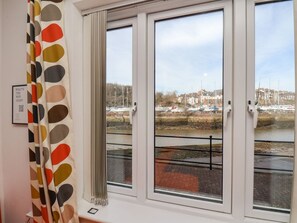 A room with a view of a river and boats, a window with a curtain, and a sign on the wall. - 15 Turnbull Court, Whitby (Whitby)