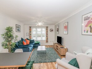A modern living room with a sofa, coffee table, TV, and a dining table. - 15 Turnbull Court, Whitby (Whitby)