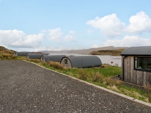 A gravel path leading to cylindrical storage tanks and a wooden building with a metal roof.