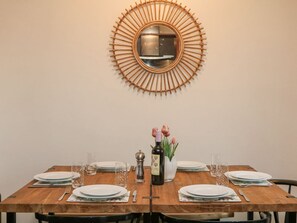 A dining table set with plates, glasses, cutlery, and a bottle of wine, with a decorative mirror above. - Sylvannah, Buxton, Derbyshire. (Buxton)