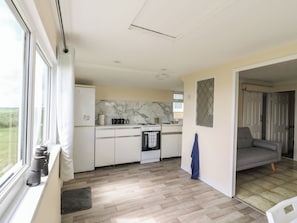 Una cocina compacta con ventana, estufa y lavamanos.