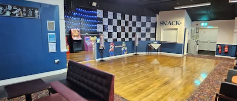 A room with a patterned carpet, a bench, a wall with framed certificates, and a wall with a 'SNACKS' sign.