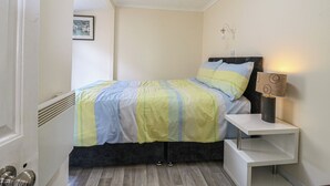 A bedroom with a bed, bedside table, lamp, and a picture on the wall. - Watersmeet - 85 @ Park Avenue Holiday Village (Sheerness)