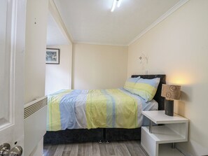 Une chambre à coucher avec un lit, une table de chevet, une lampe et un tableau au mur.