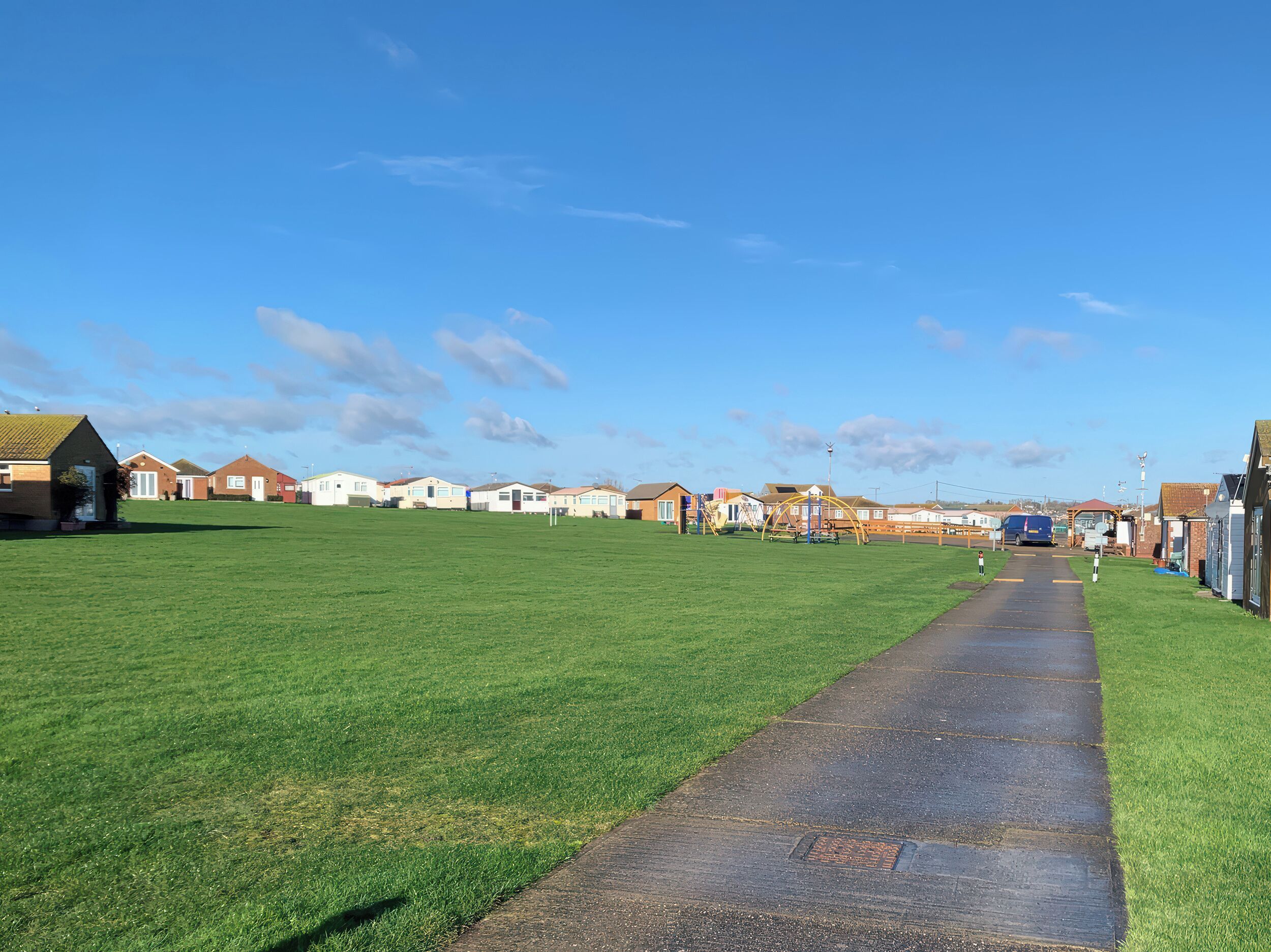 A pathway leading to a row of houses with a clear sky above.