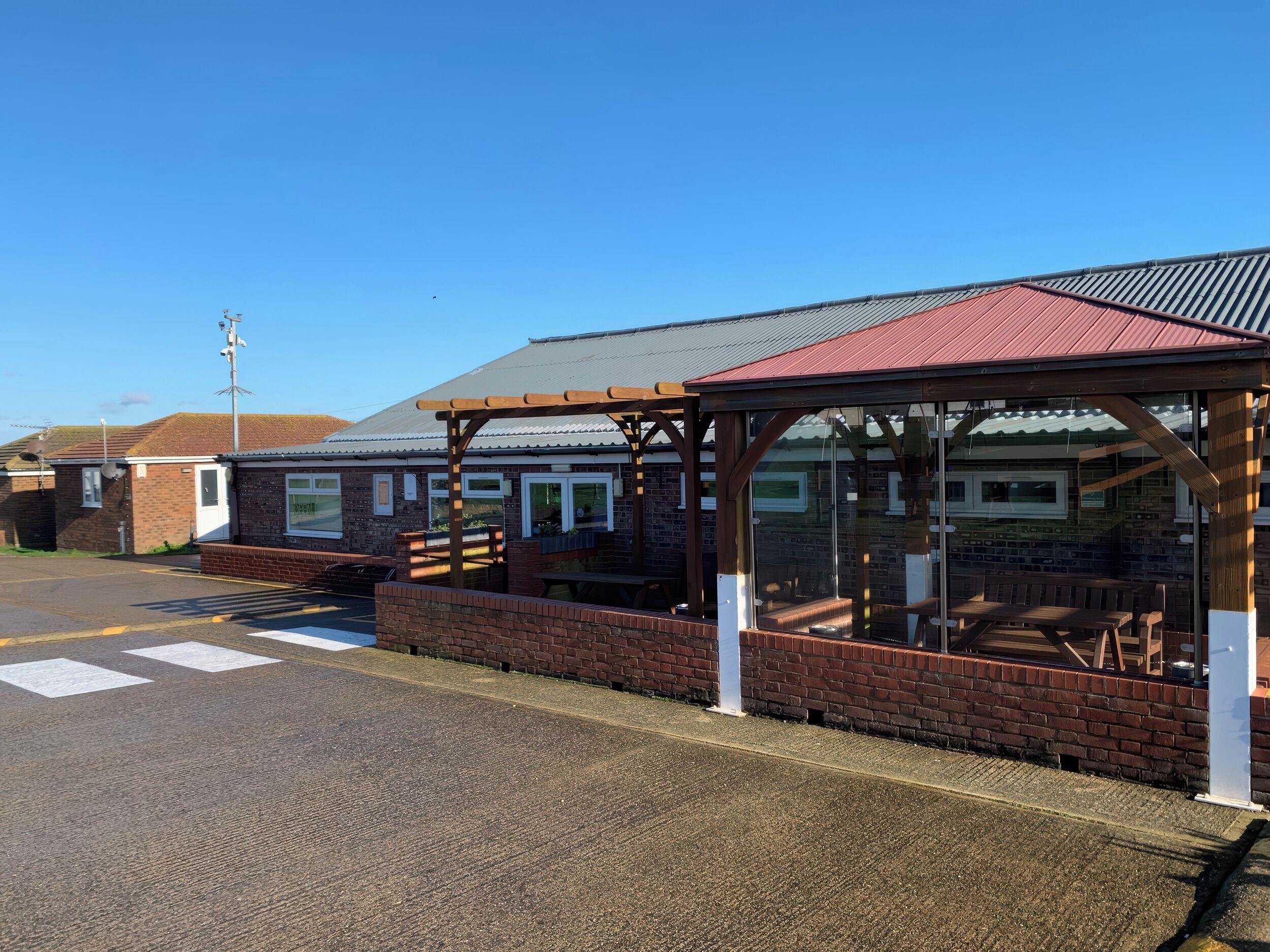 A covered outdoor seating area with a brick wall and a metal roof.