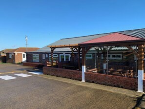 A covered outdoor seating area with a brick wall and a metal roof. - Watersmeet - 85 @ Park Avenue Holiday Village (Sheerness)