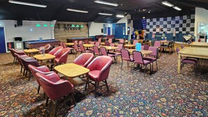 A room with tables and chairs, a patterned carpet, and a wall with a sign. - Watersmeet - 85 @ Park Avenue Holiday Village (Sheerness)