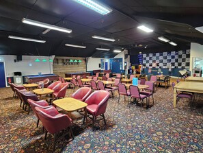Une pièce avec des tables et des chaises, un tapis à motifs et un mur sur lequel est accroché un panneau.